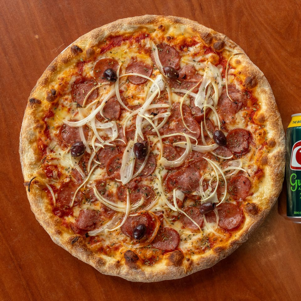 NY Pizza Patrol pepperoni pizza with onions and olives, next to a can of soda.