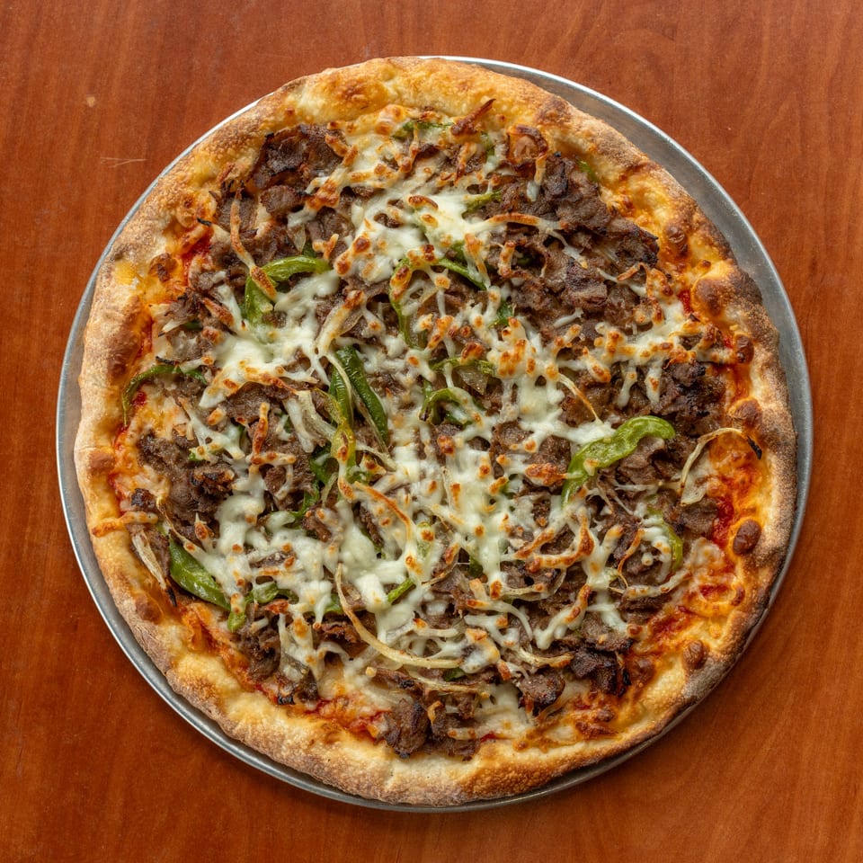 NY Pizza Patrol's Philly cheesesteak pizza, topped with steak, green peppers, onions, and melted cheese.